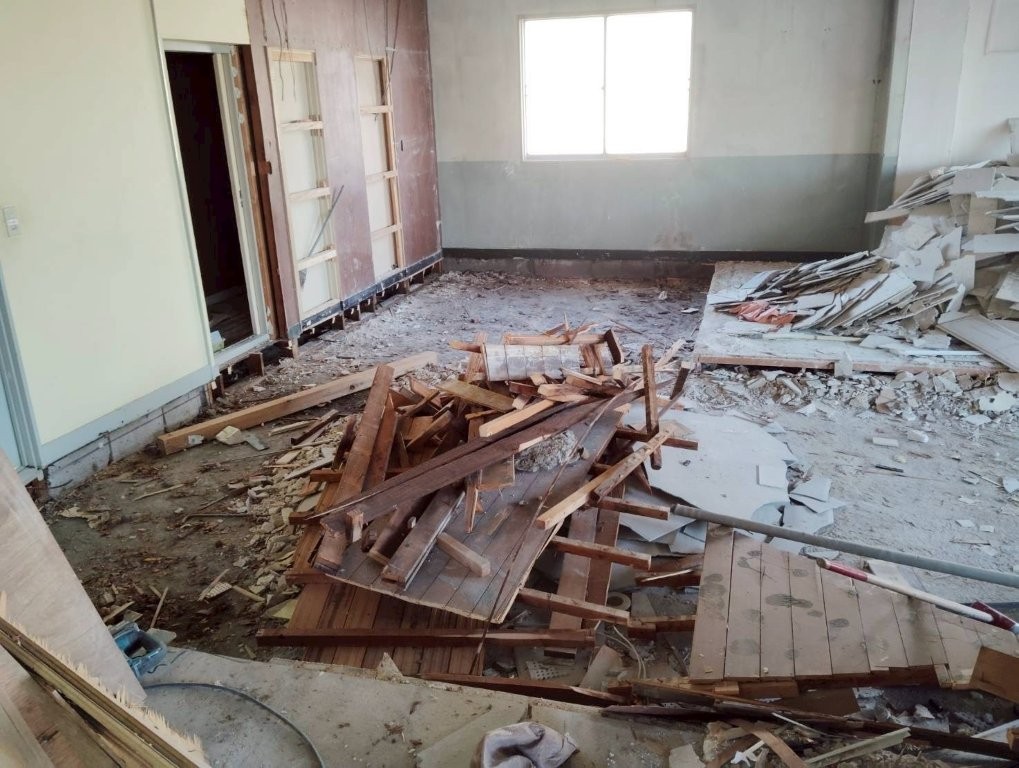 内装解体工事中の撤去材集積｜木材（床板・根太・造作材）の山積みと切断作業の様子