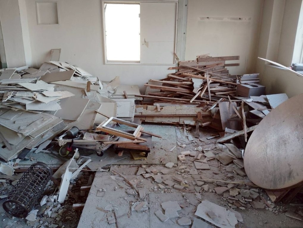 原状回復のためのスケルトン解体｜床材撤去途中の区画と木材・ボード片の分別集積
